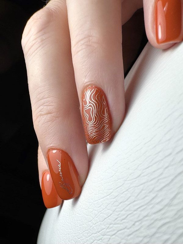Manicura terracota con líneas doradas